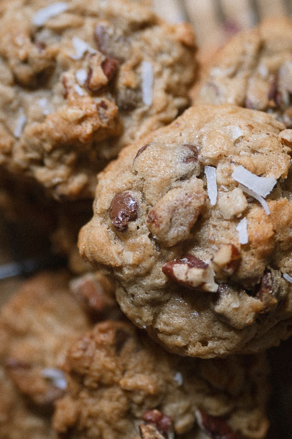 Close-up macro shot of homemade oatmeal cookies with chocolate chips and shredded coconut sprinkled on top.