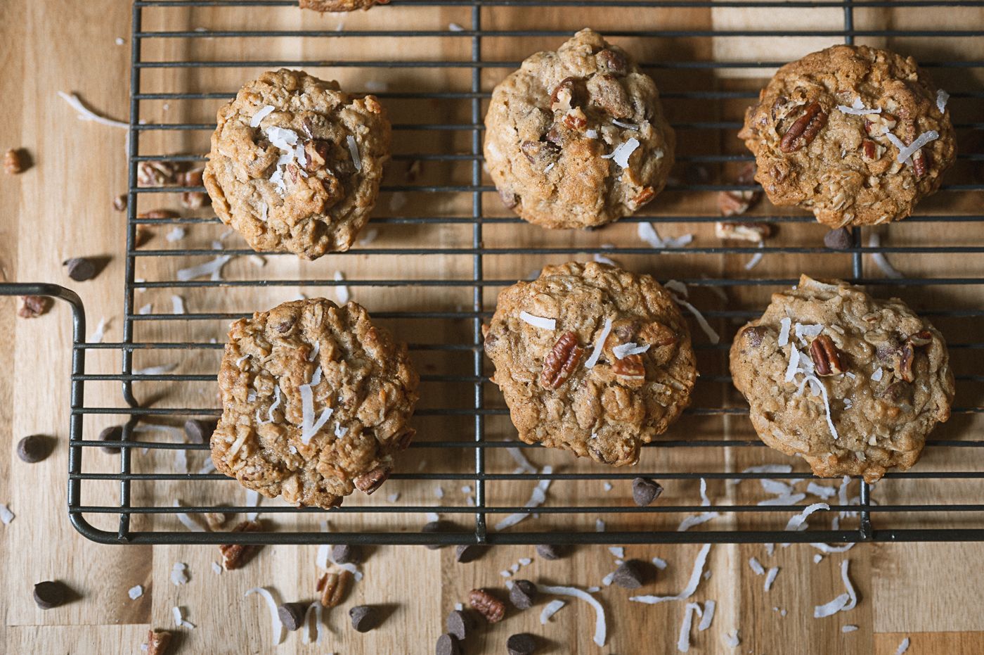 Freshly baked chocolate chip cookies cooling on a wire rack with parchment paper underneath.