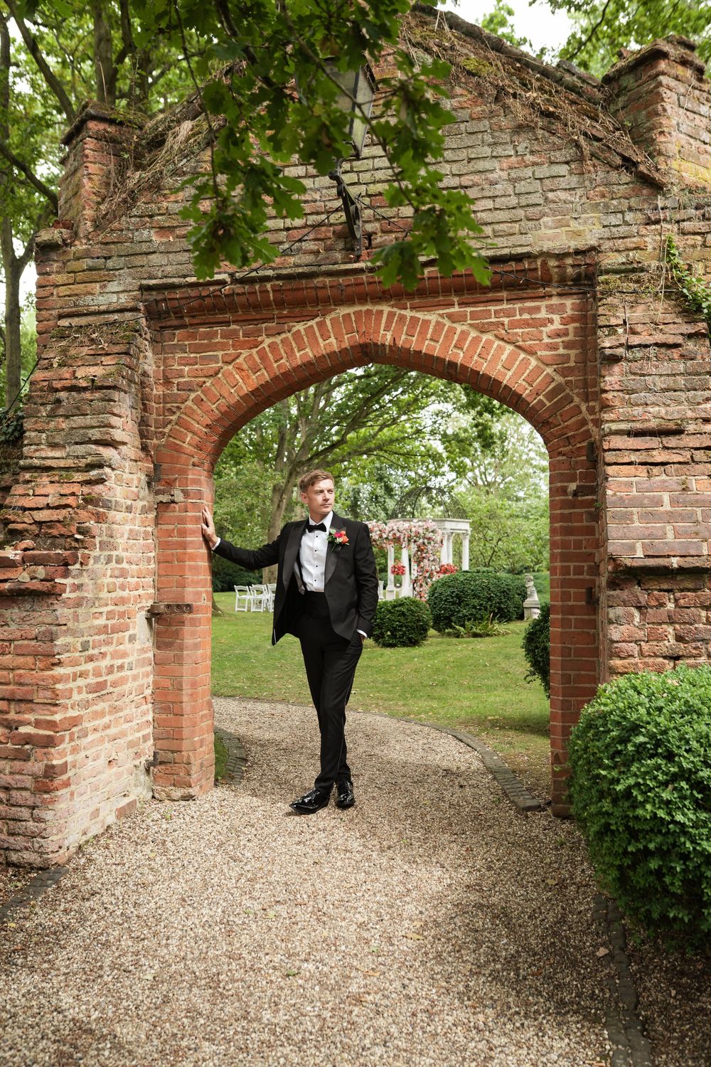 Multiple brick archways along a gravel path create an elegant garden walkway with greenery overhead.