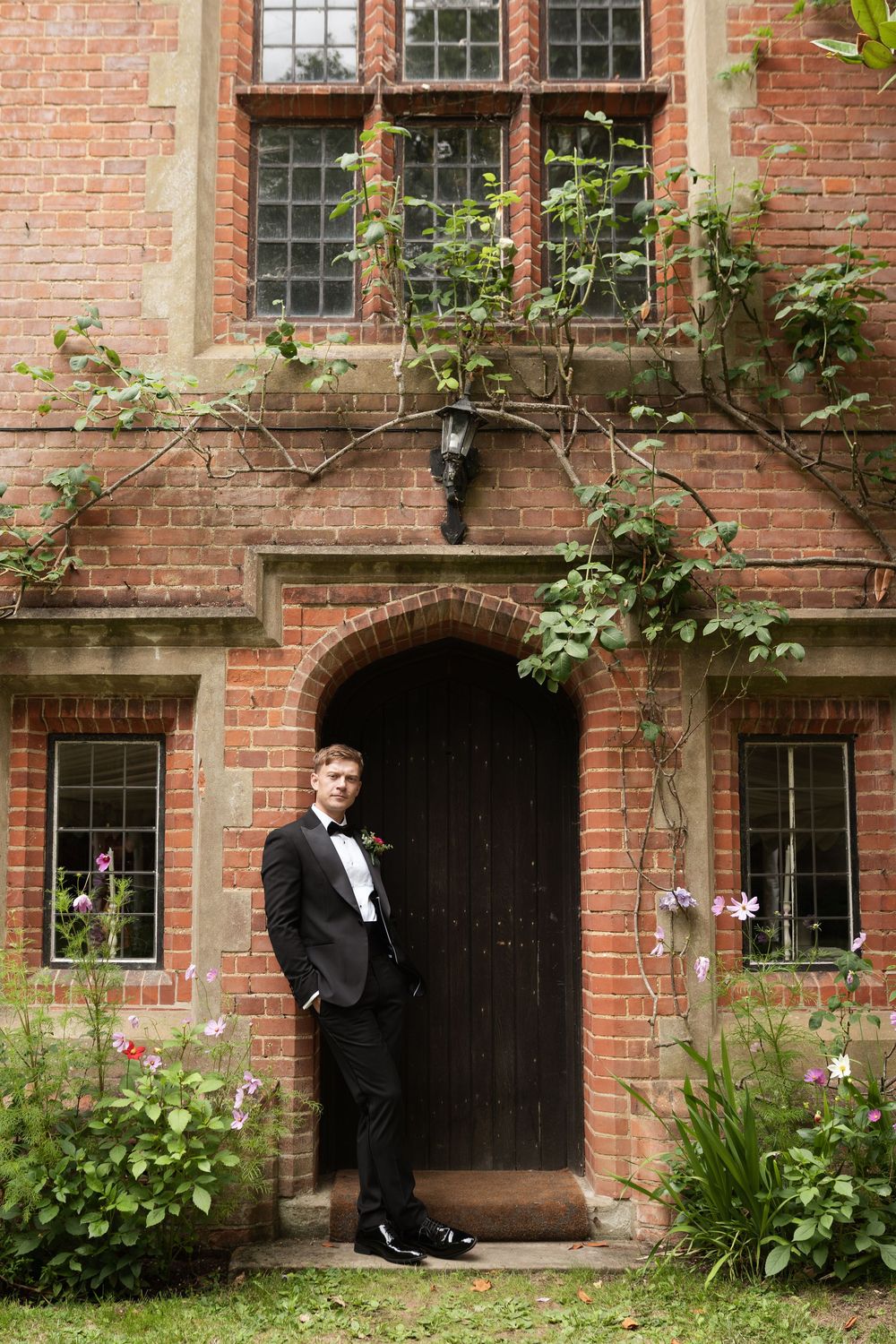 Wedding photos taken in front of rustic brick building with arched doorways and climbing vines.