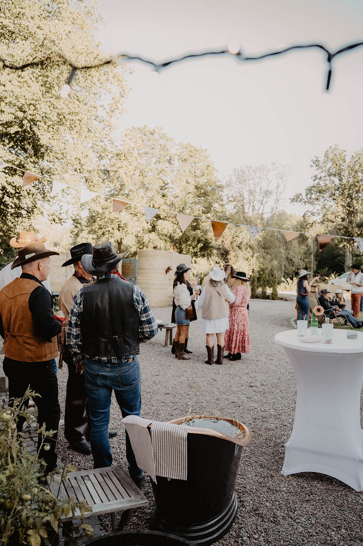 Gäster minglar bland höbalar på en dekorerad gårdsplan under cowboyfest, fotograferat av eventfotograf Josefin Landhagen i Östergötland