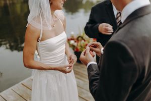 A couple exchanging vows during an outdoor wedding ceremony by a lake.