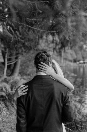A black and white photo capturing an emotional embrace during a wedding.