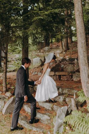 A wedding ceremony taking place on a wooded hillside with pine trees and natural scenery.
