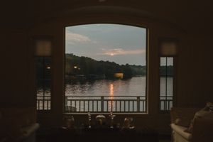 Guests gather around a table on a lakeside deck for a celebratory meal.