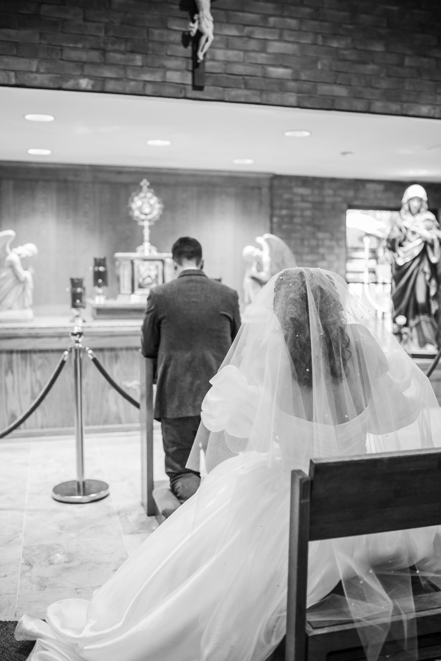 Black and white photo of a couple at their wedding ceremony with bride in white dress and groom in dark suit.
