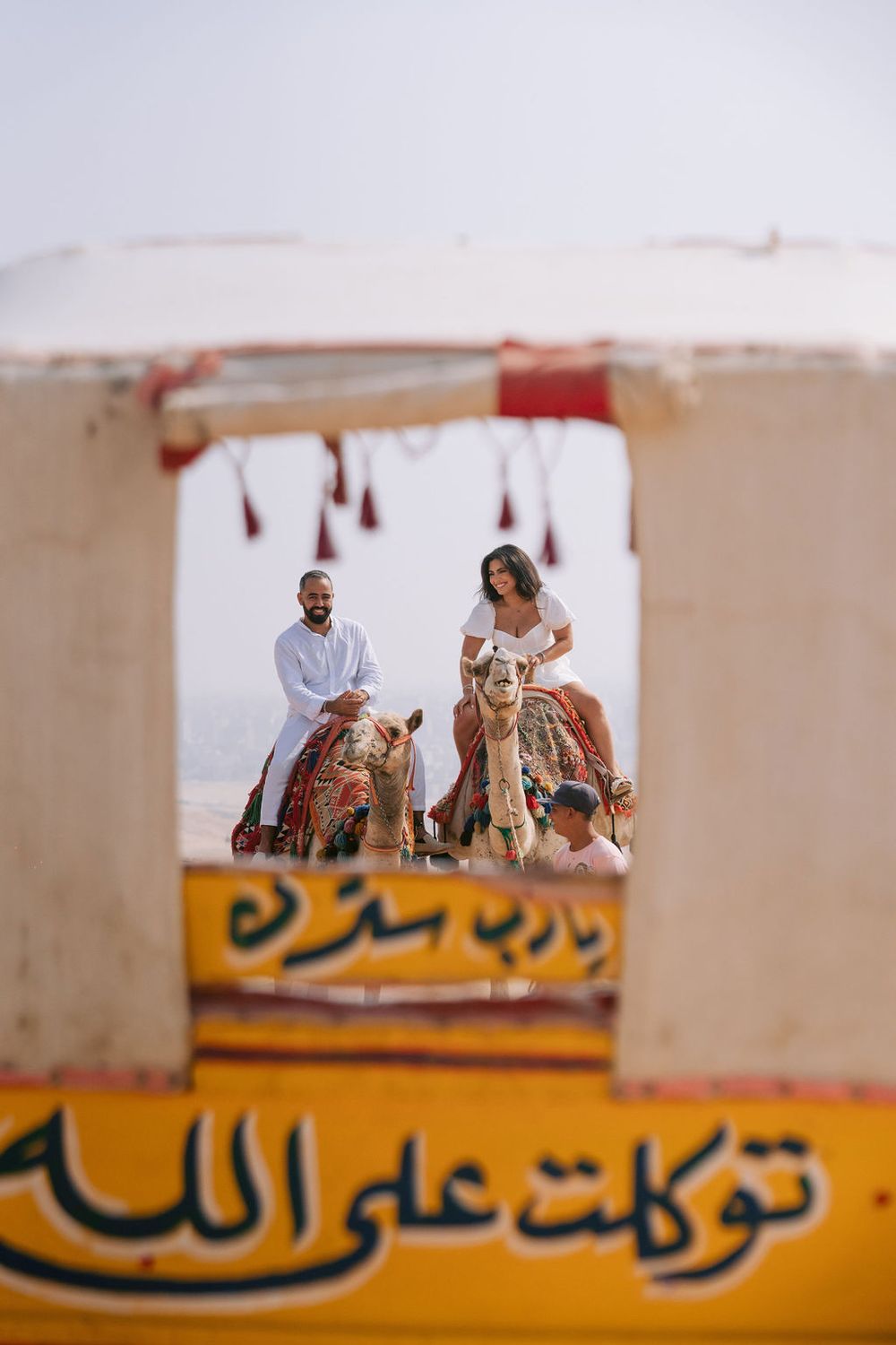 Middle Eastern Arabic text is visible on yellow signage with people appearing blurred in the background against a light wall.