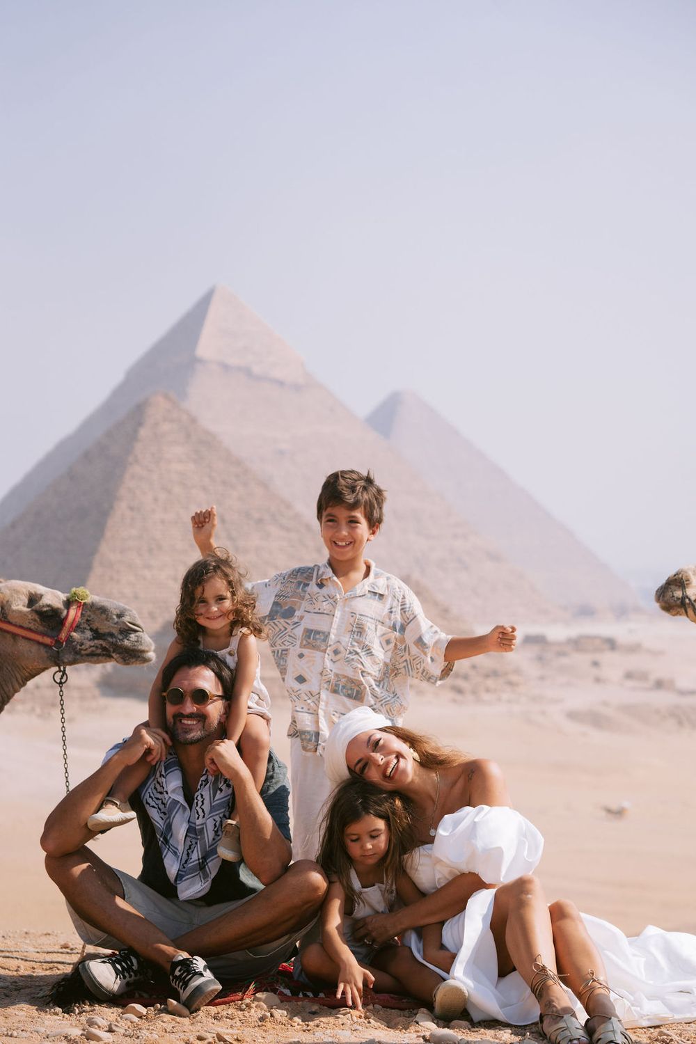 A group sits together in casual attire against the stunning backdrop of the ancient Egyptian pyramids at Giza in the desert.