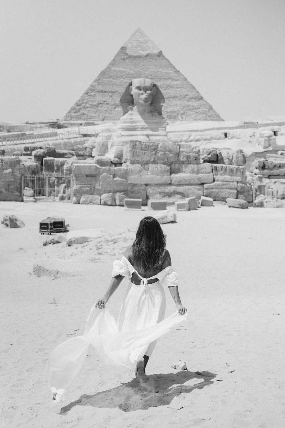 A series of black and white photos showing someone in white clothing posing in front of the Great Sphinx and pyramids of Giza.
