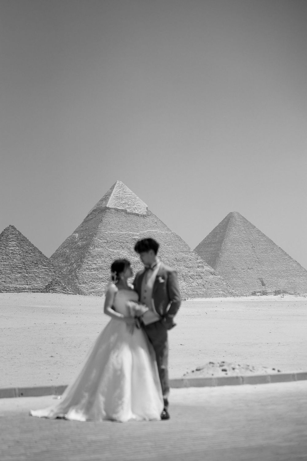 A series of wedding photos taken at the iconic Great Pyramids of Giza in Egypt showing the couple walking in desert landscape.