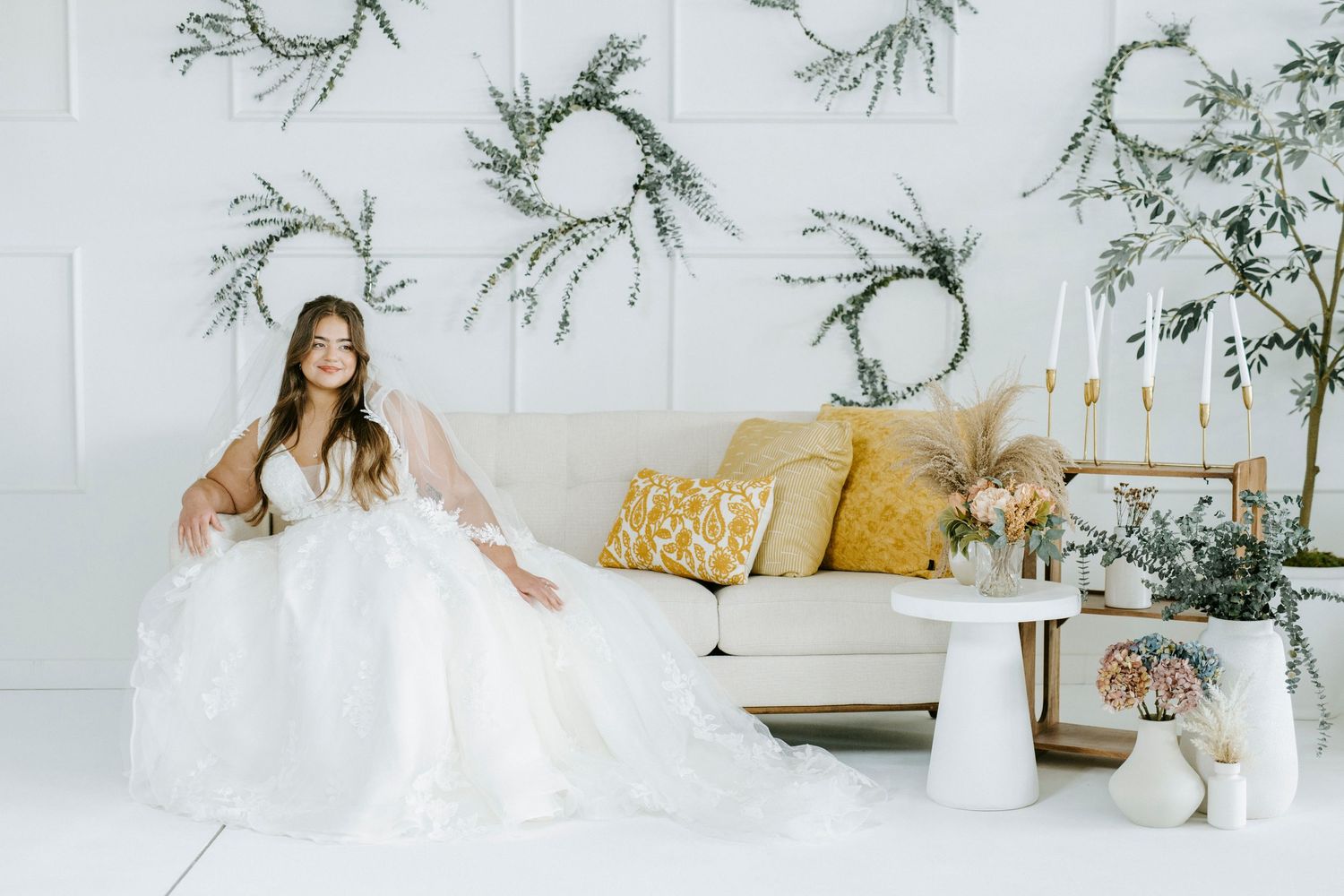 Elegant minimalist white living room interior with dried branch decor and neutral toned textiles.