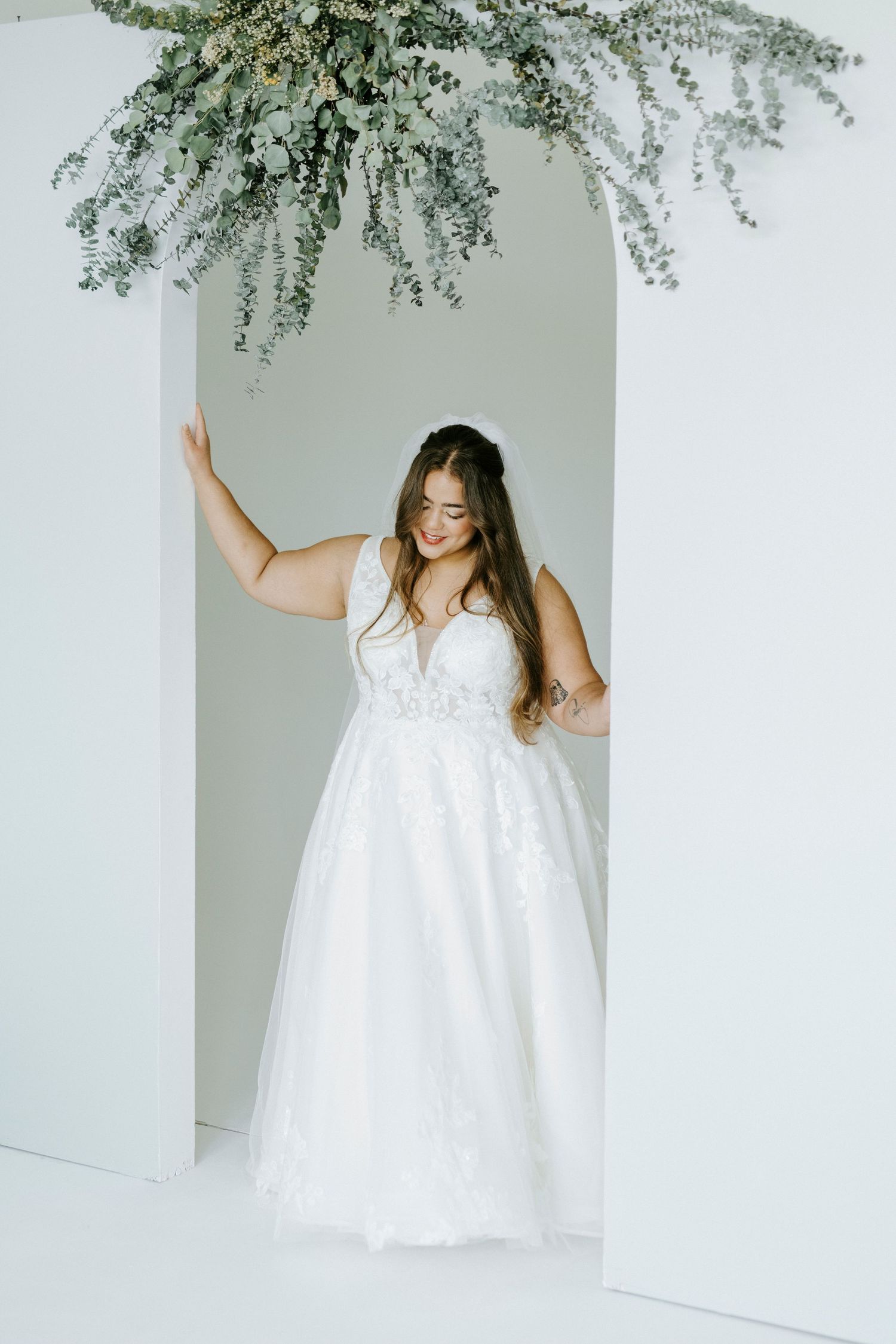 A series of four photos showing someone in a flowing white dress twirling and dancing in a minimalist studio setting.