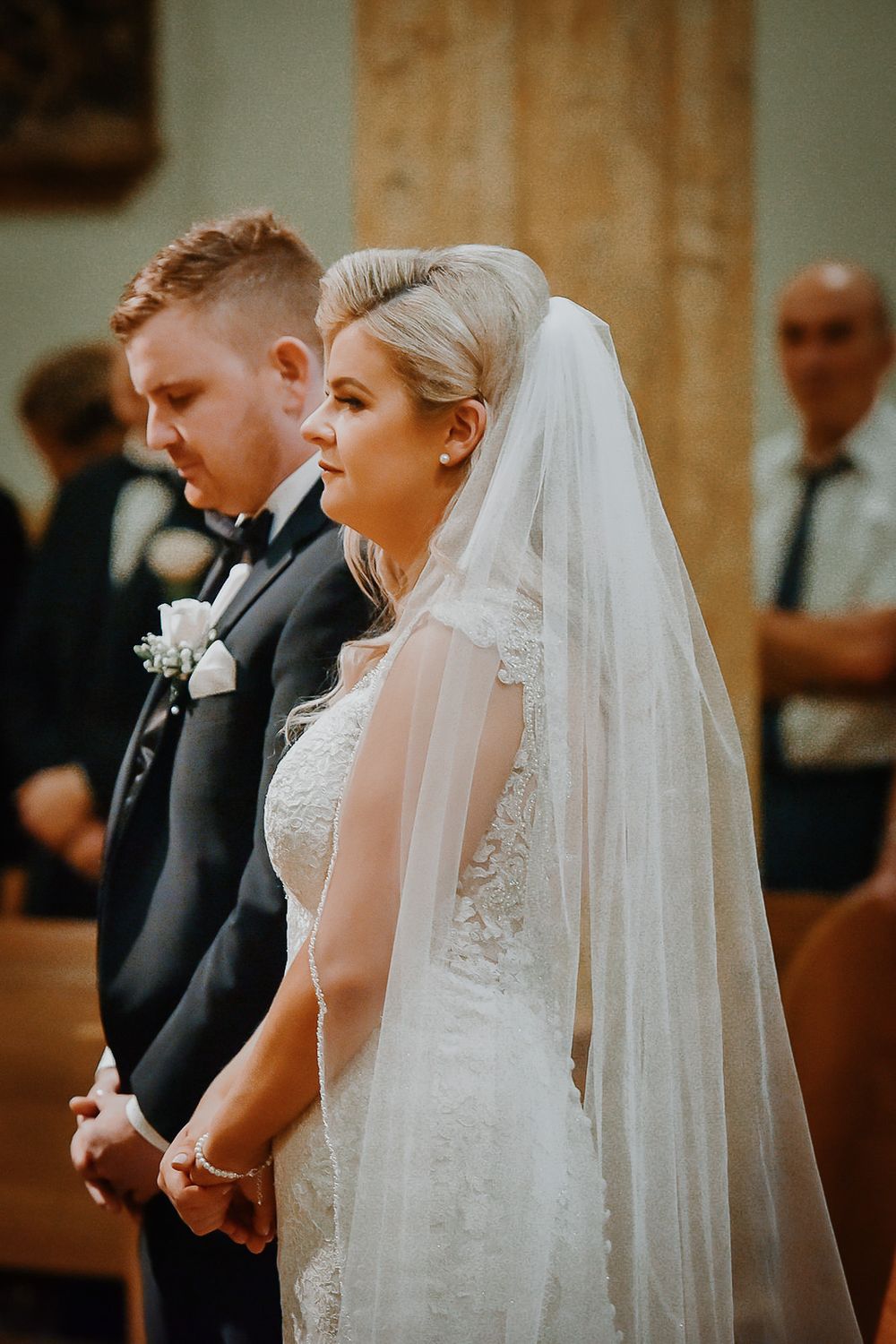 A couple shares an intimate church wedding ceremony moment with bride wearing traditional white dress and veil.
