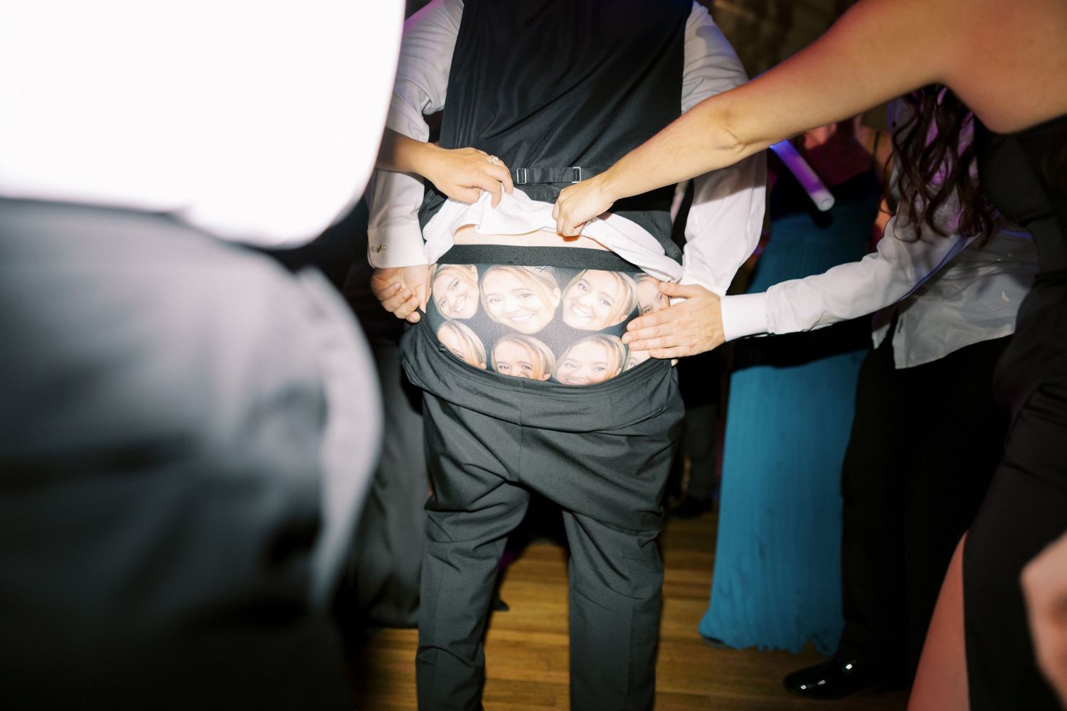 Group of people having fun dancing together at a reception or party on a wooden dance floor.
