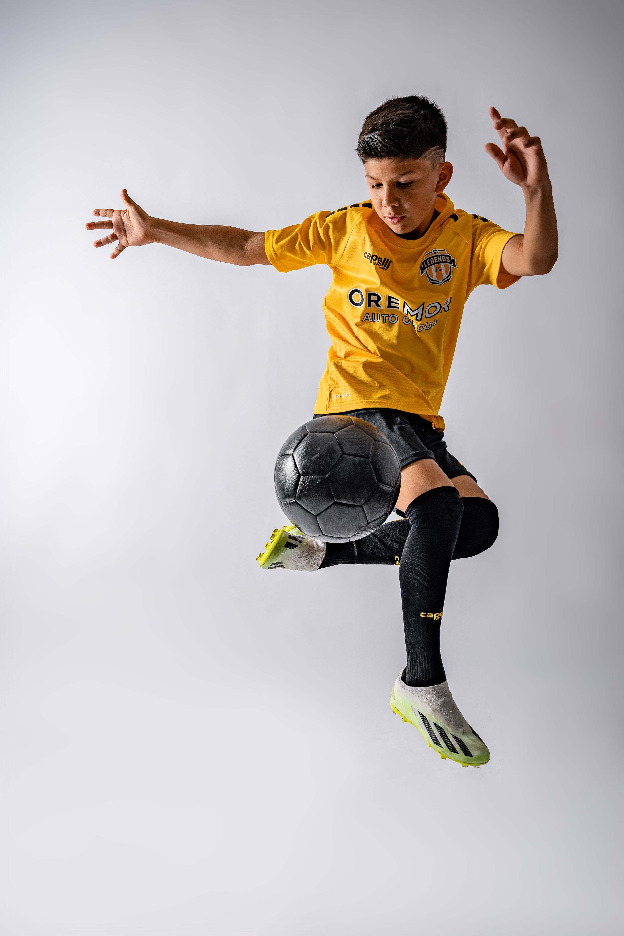 Athletic figure in yellow jersey and dark pants performs dynamic jumping movements against white background.