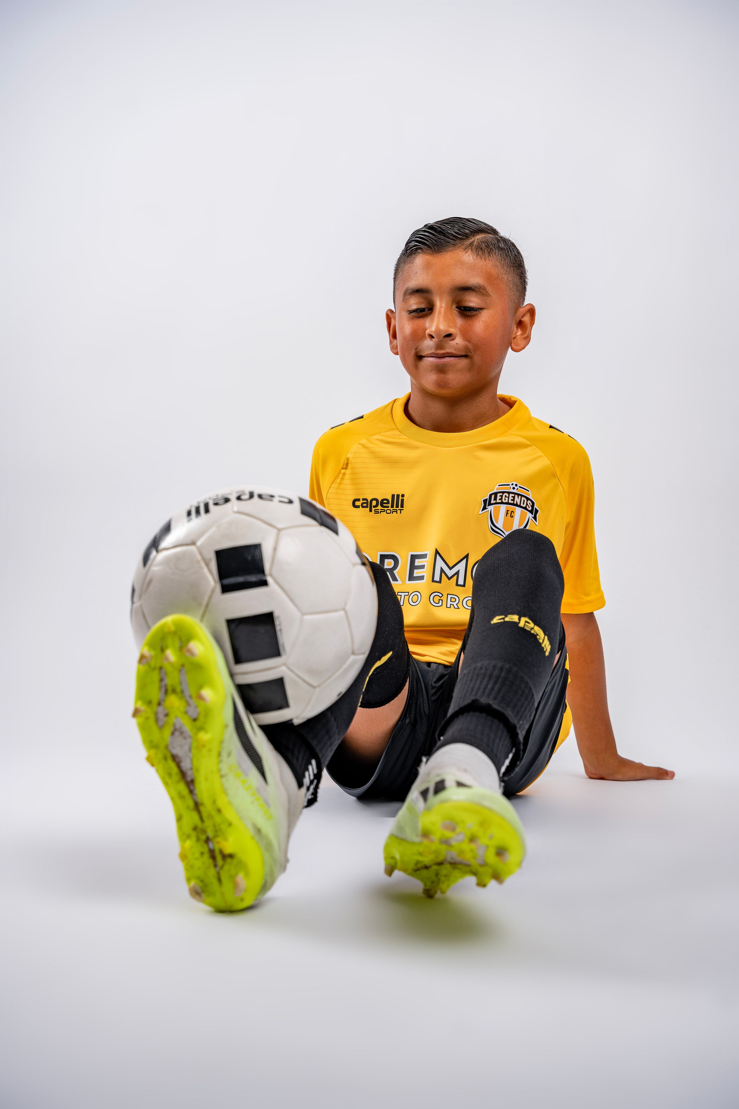 Multiple frames of a youth soccer player's feet posing with a soccer ball against a white studio background.