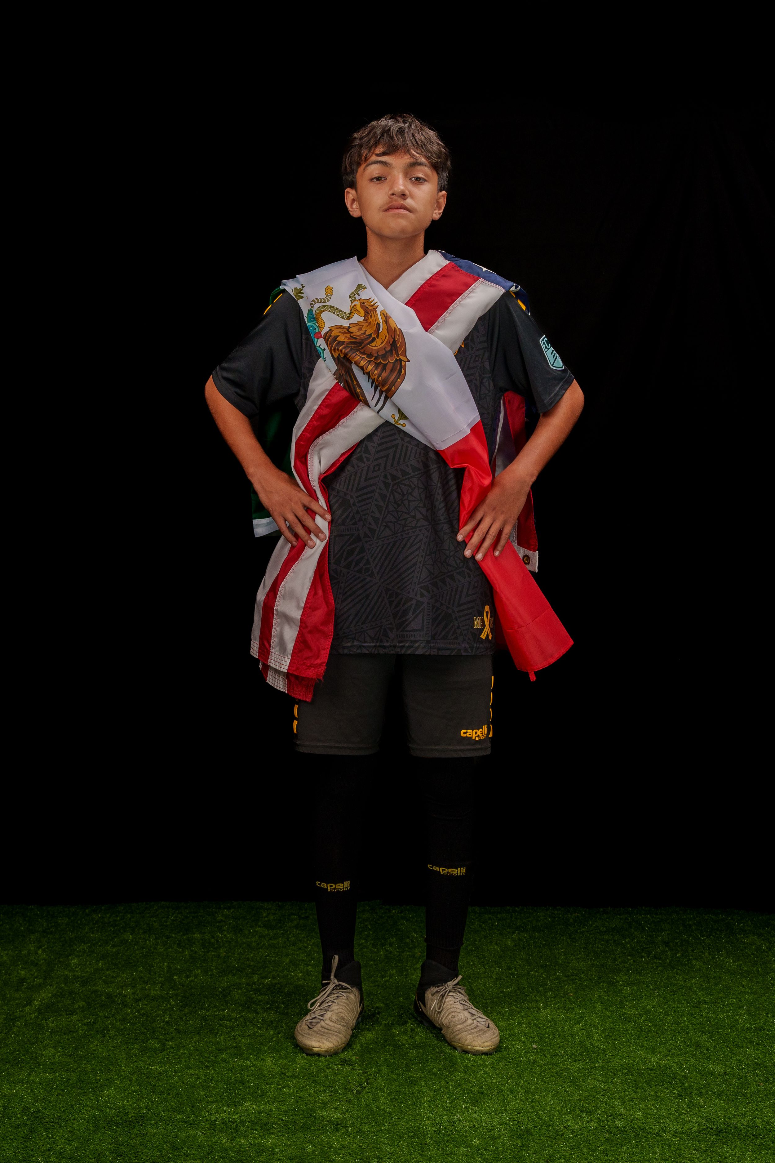 Athletic player standing on green turf wearing soccer uniform with red and white sash in dynamic poses.