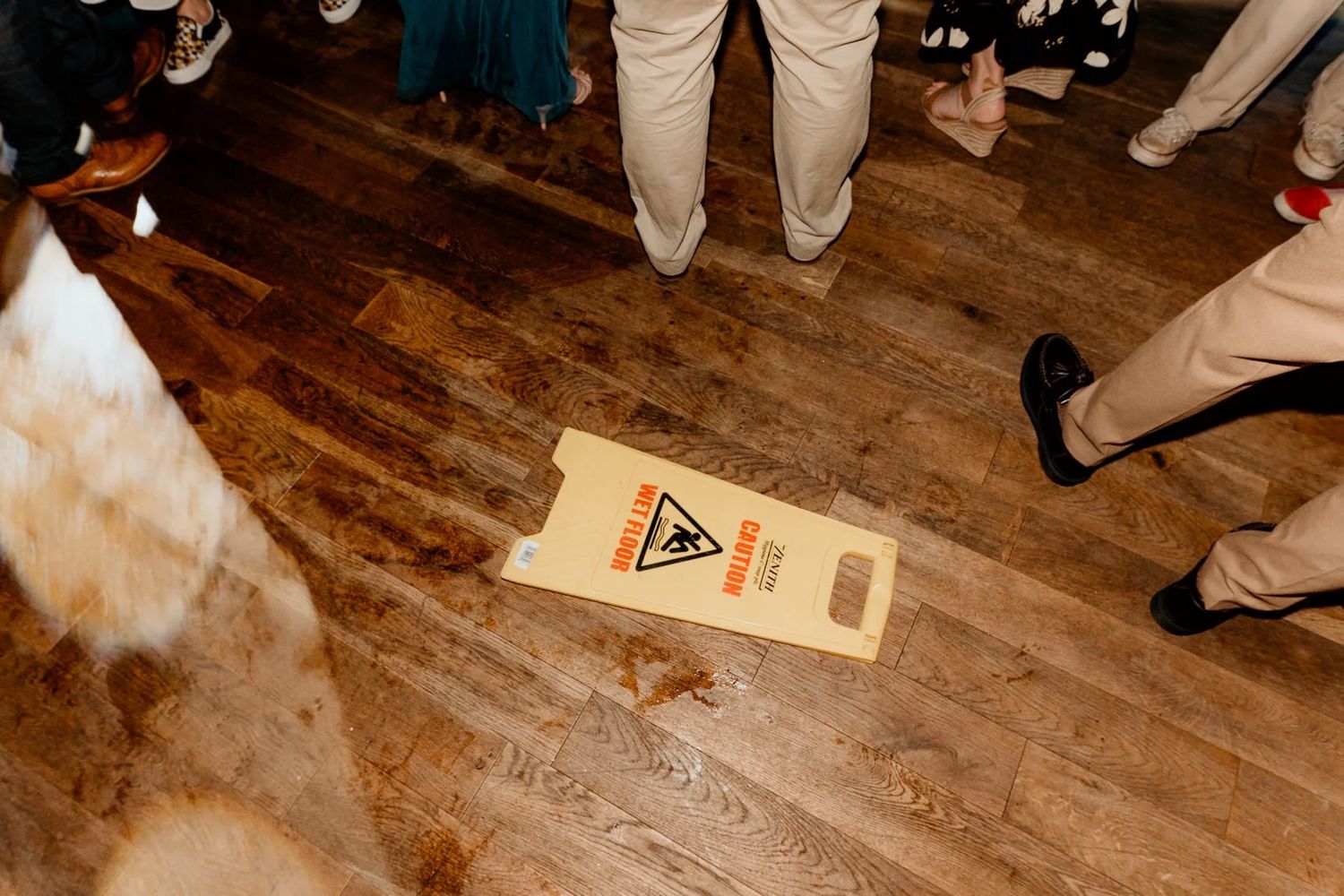 Wedding guests dance on a rustic wooden floor during the reception celebration.