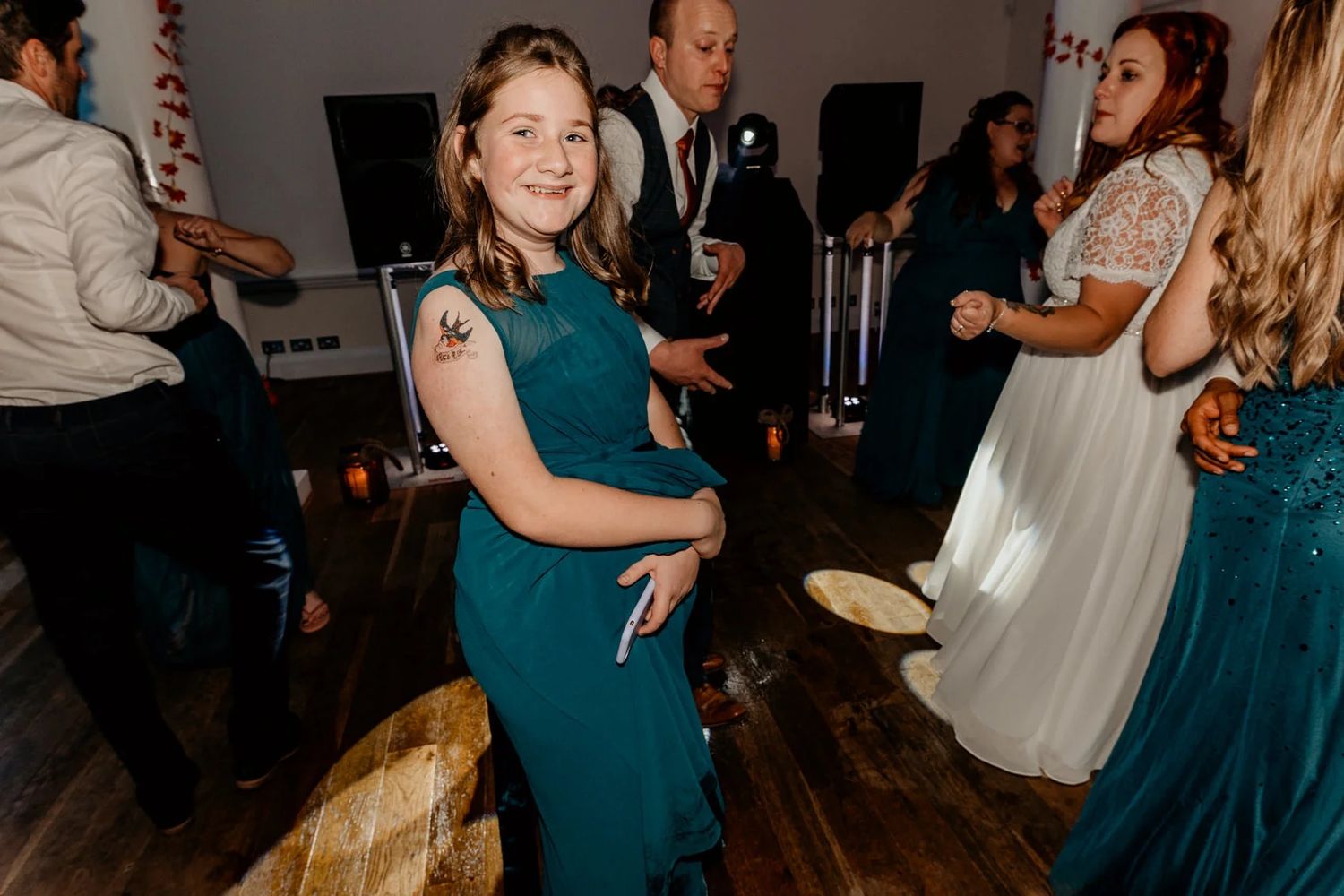 Wedding reception dance floor with guests in formal attire and teal bridesmaid dresses.