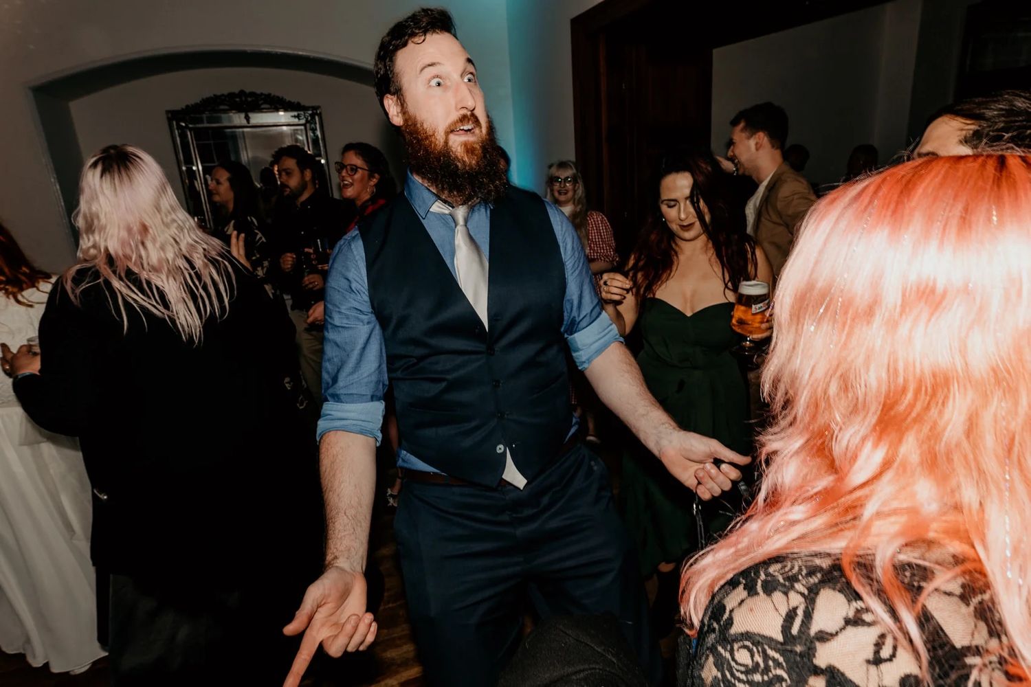 Dance floor celebration with colorful lighting at wedding reception.
