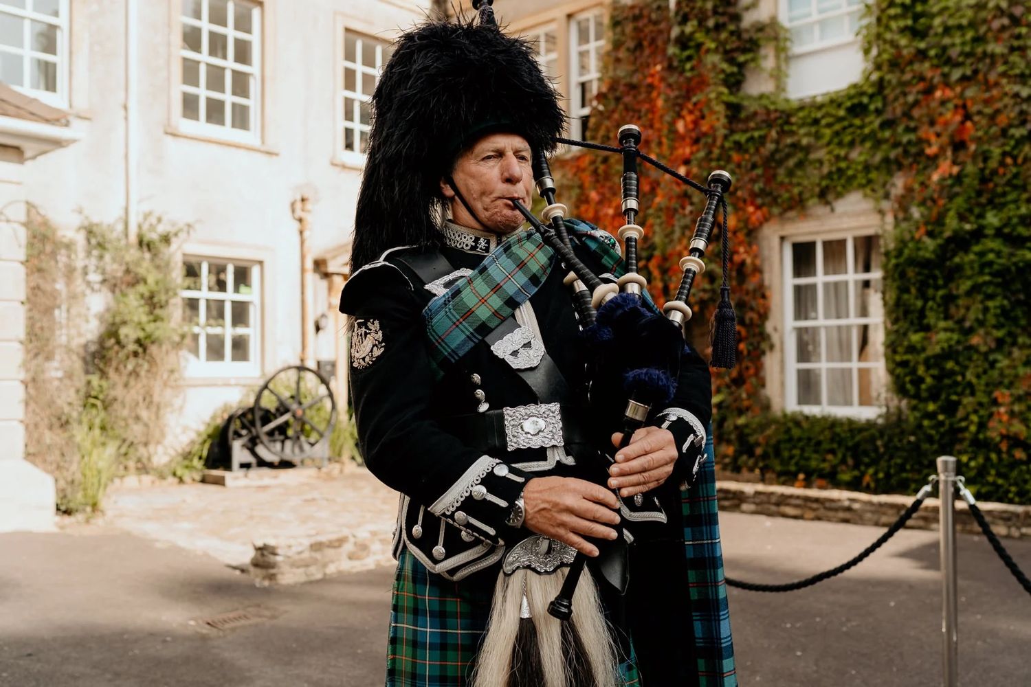 A bagpiper in traditional Scottish attire plays during an elegant outdoor event.