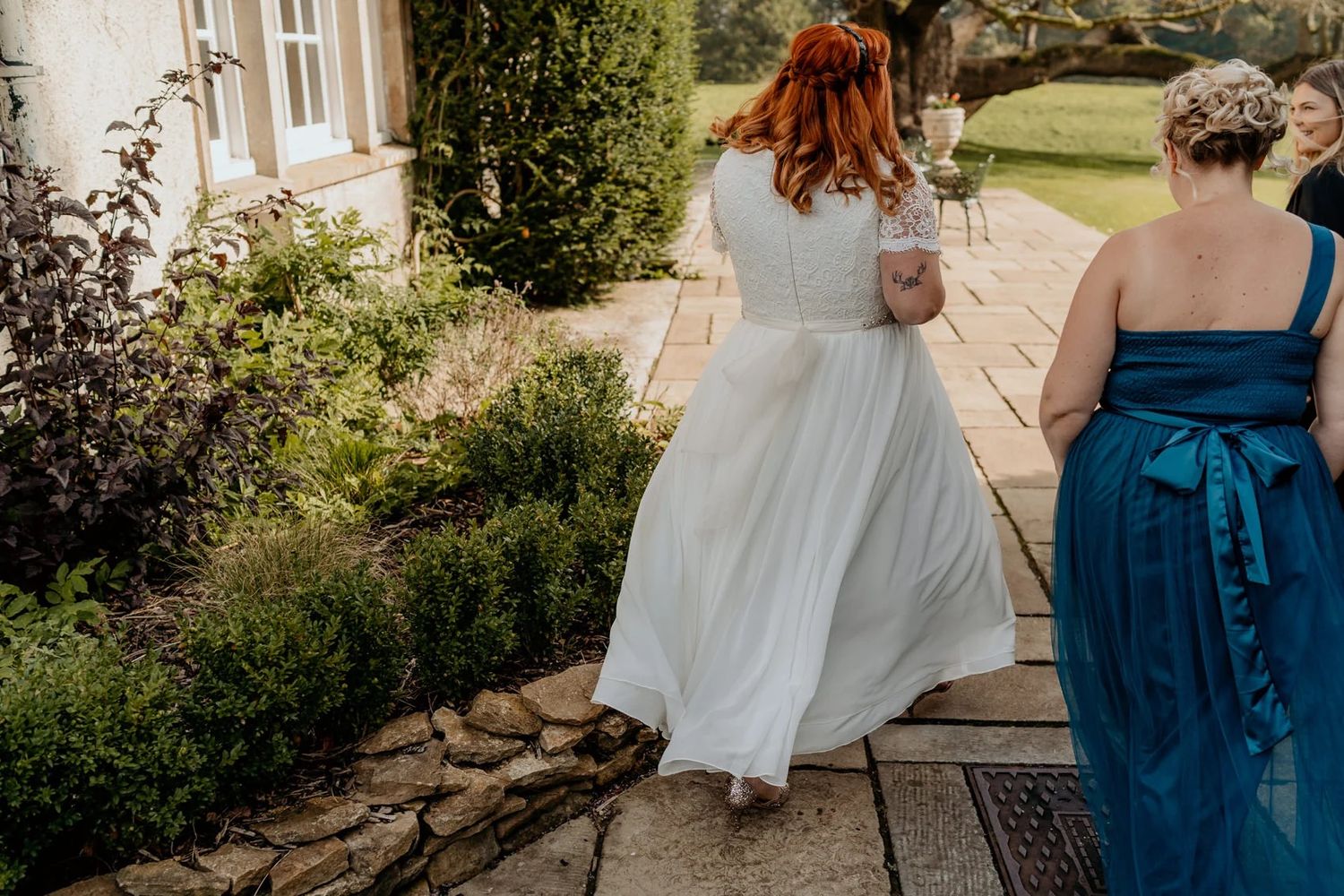 Garden wedding ceremony setup with guests seated on white chairs along a stone pathway.