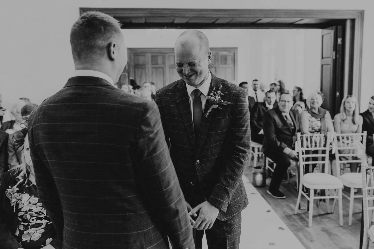 An emotional black and white moment during an indoor wedding ceremony.
