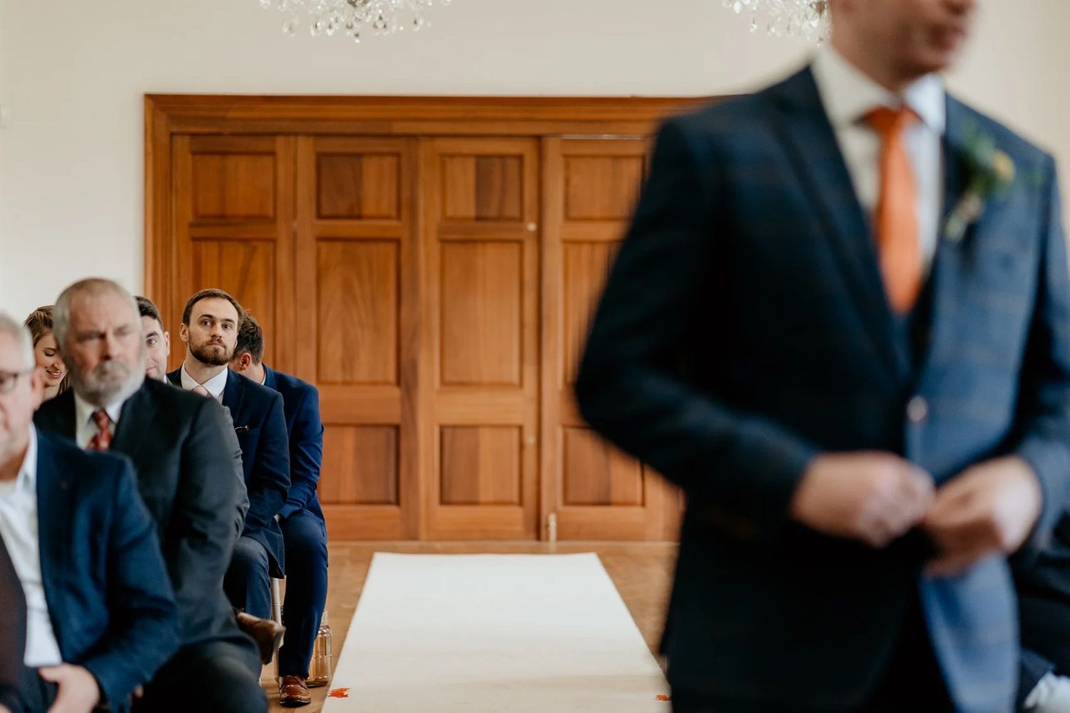 Wedding ceremony attendees gathered in an elegant wood-paneled room for indoor celebration.