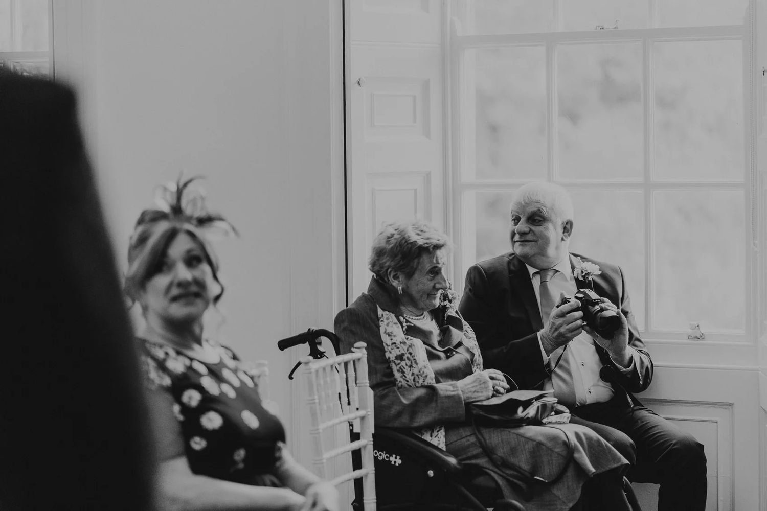 Candid black and white shot of wedding guests laughing during the reception.