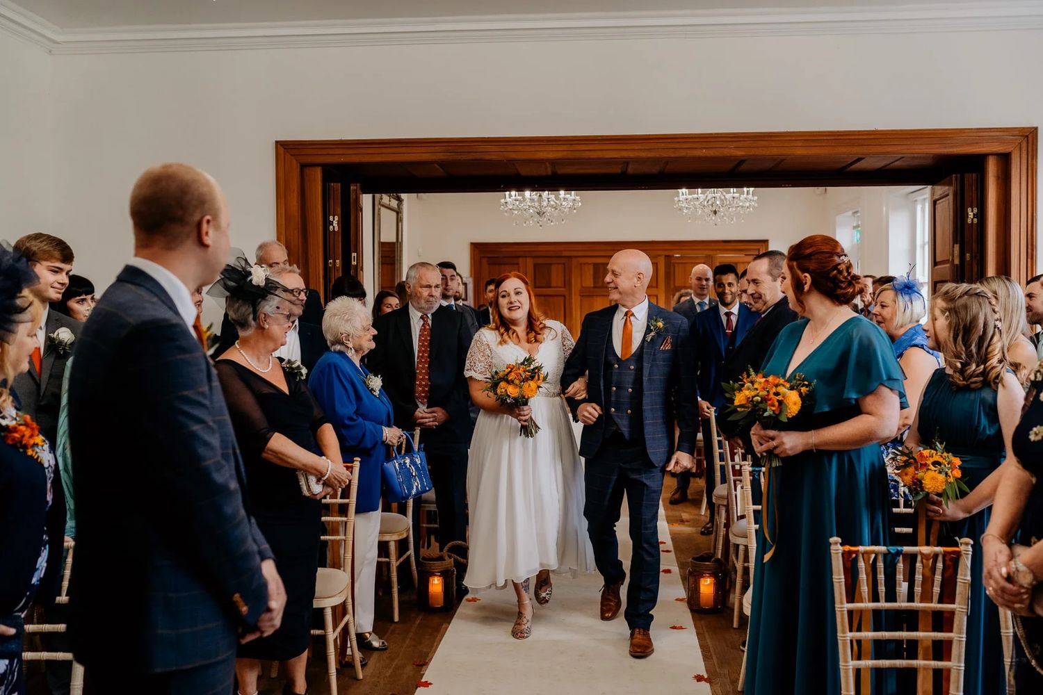 Wedding reception space with dark wood paneled walls and guests socializing during cocktail hour.