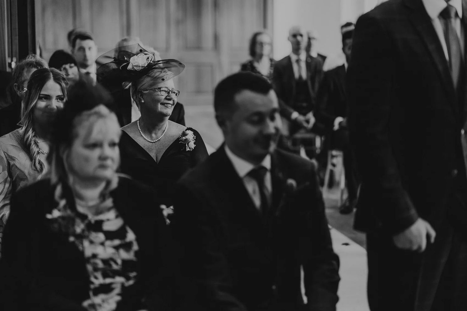 Black and white photo of wedding guests gathering in an elegant reception venue.