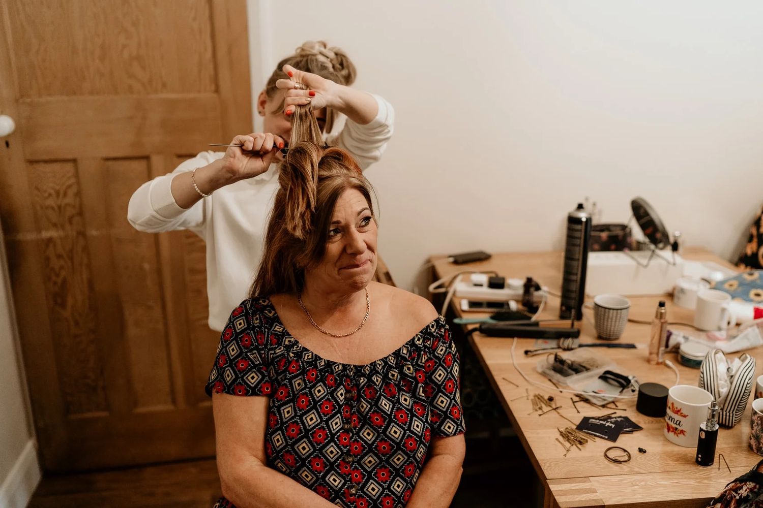 A photo montage showing the progression of a hairstyling and makeup preparation session at a dressing table.