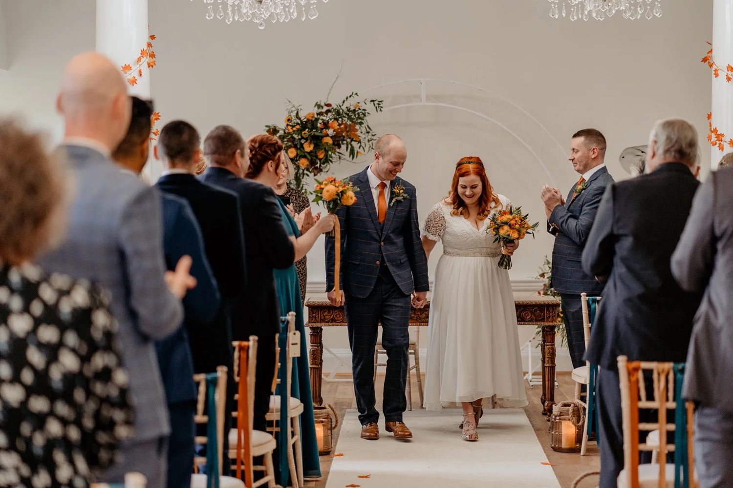 Guests gathered inside an elegant venue with chandelier lighting for a formal wedding celebration.