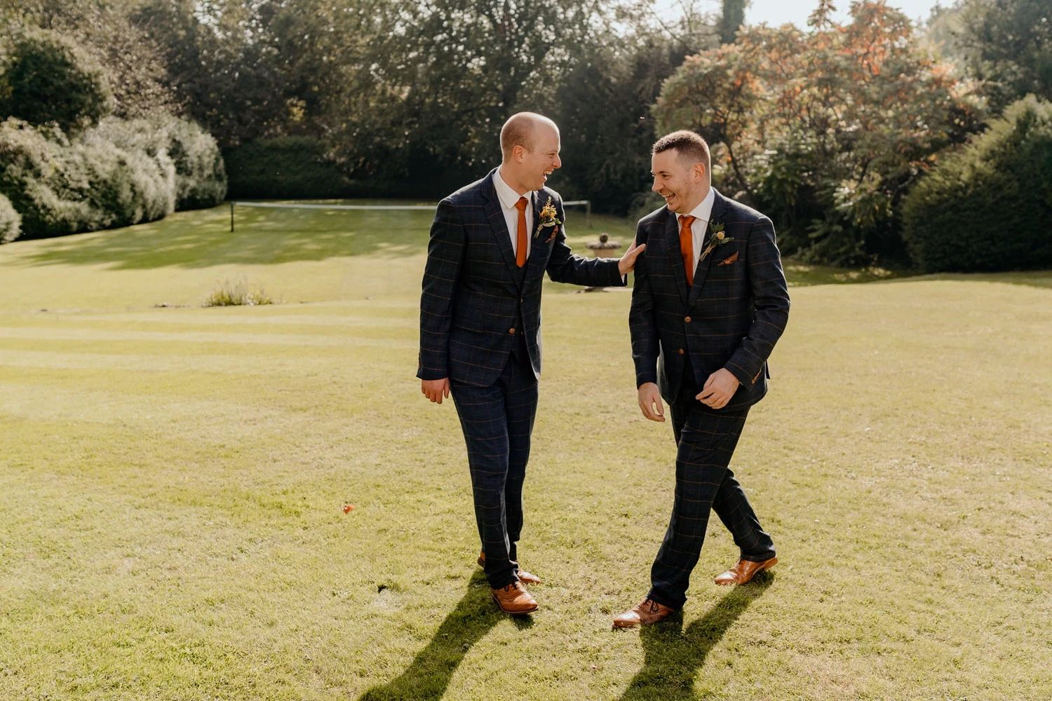 Wedding party walking and laughing together on sunny lawn.