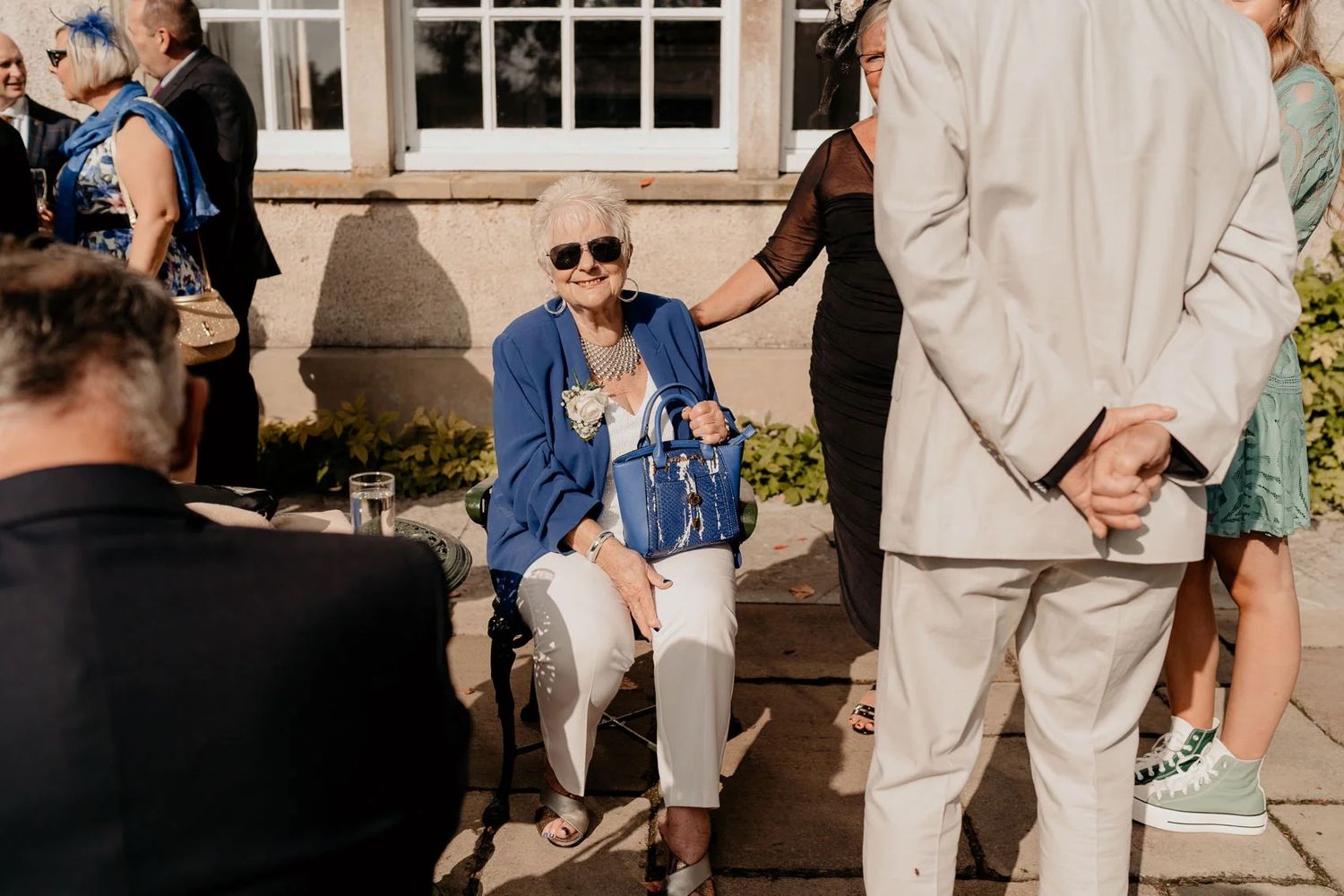 Outdoor wedding reception with guests in formal attire enjoying conversations.