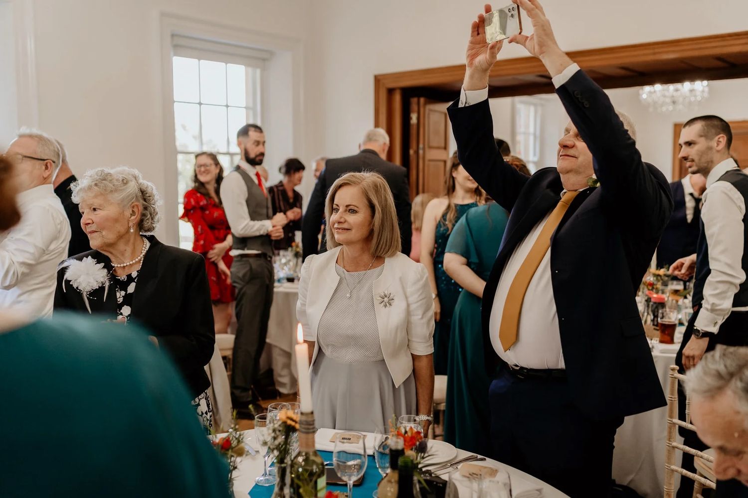 Wedding guests mingle and socialize during a reception in an elegant indoor venue setting.