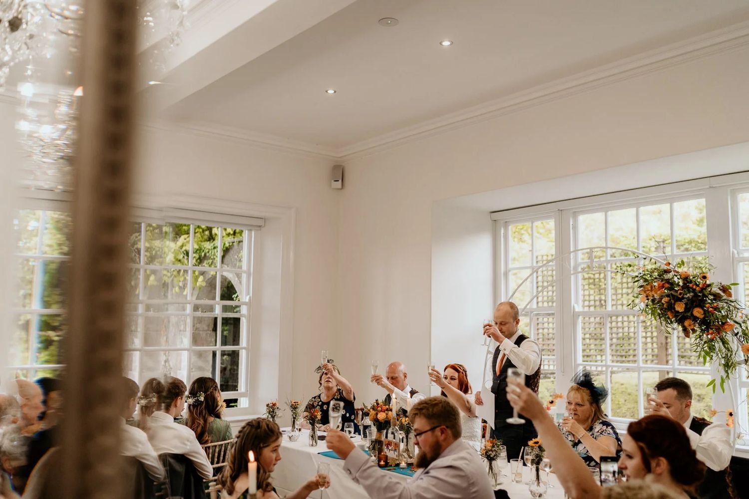 Joyful wedding guests raise their hands in celebration during the reception.