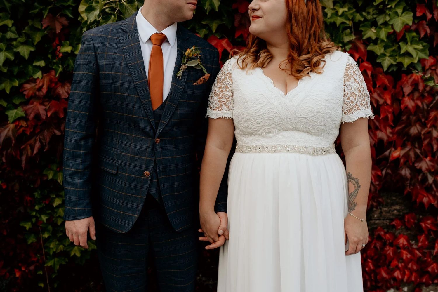 Wedding portraits with red autumn ivy backdrop and navy suit details.