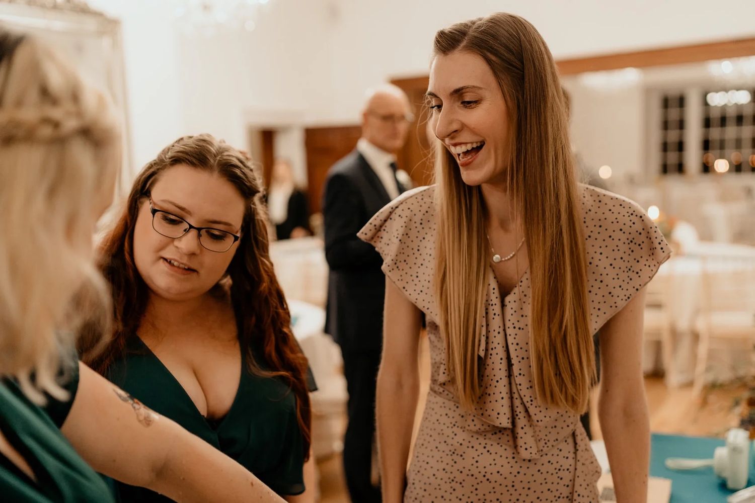 Wedding reception guests sharing laughter and conversation at indoor venue.