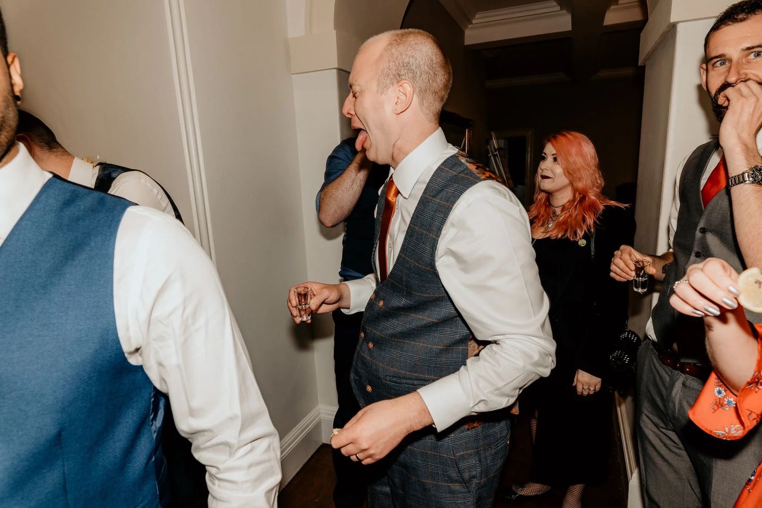 Guests dancing and celebrating at an indoor wedding reception party with dark and light contrasts.