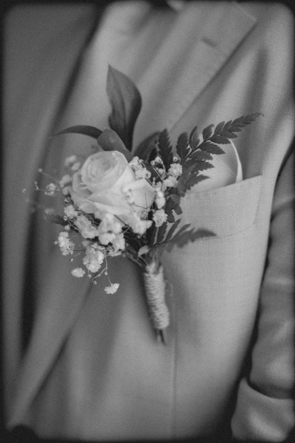 A row of matching white floral boutonnieres with delicate greenery arranged for a formal wedding celebration.