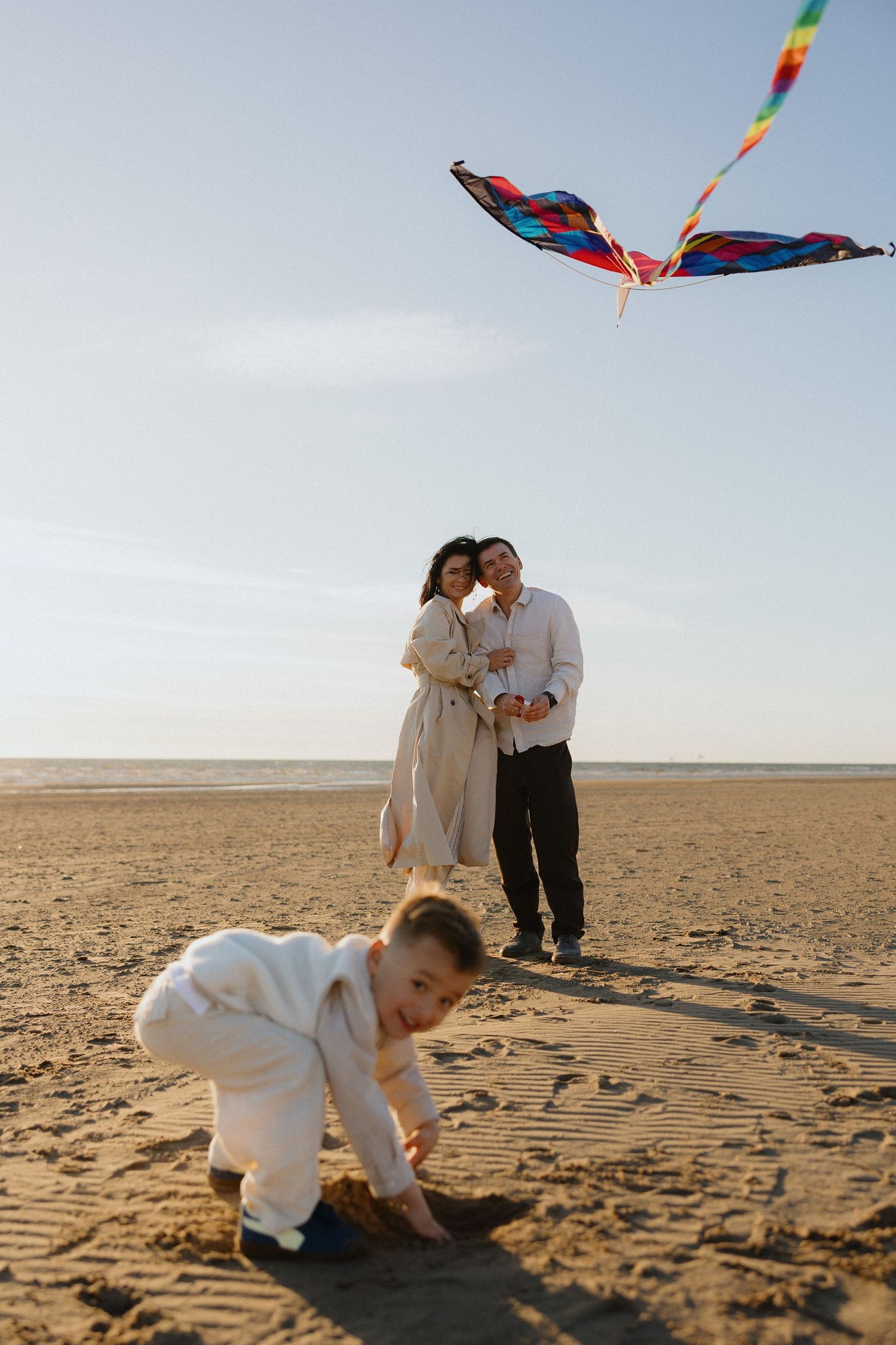 Couple sitting together on sandy beach dunes with ocean view on a sunny day.