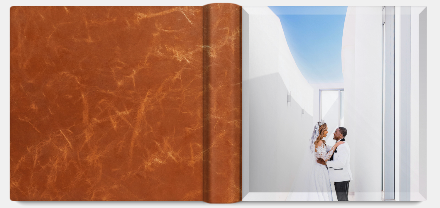 A brown leather photo album cover next to an open wedding photo showing a couple in a white hallway.