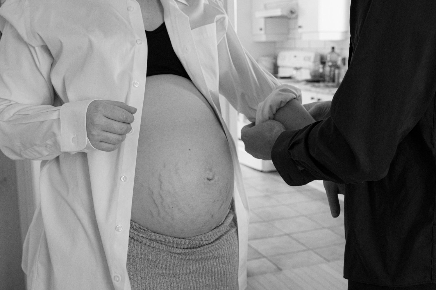 Close-up of a pregnant woman's bare baby bump with a hand gently touching the belly.