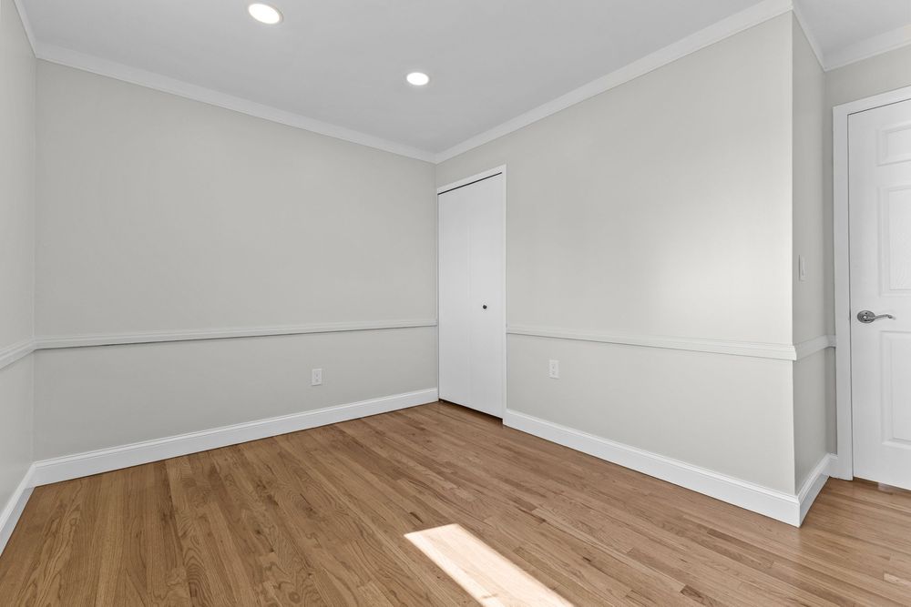 Empty room with light hardwood floors, crown molding, recessed lighting, and white closet door.