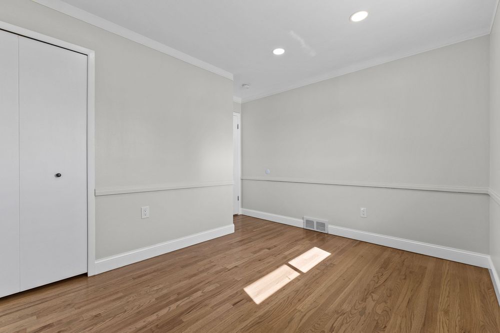Vacant bedroom with hardwood floors, crown molding, white closet door, and recessed ceiling light.