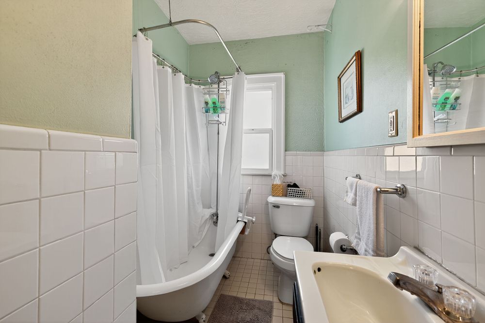 Classic bathroom with clawfoot tub, white subway tile, pedestal sink, and shower curtain.