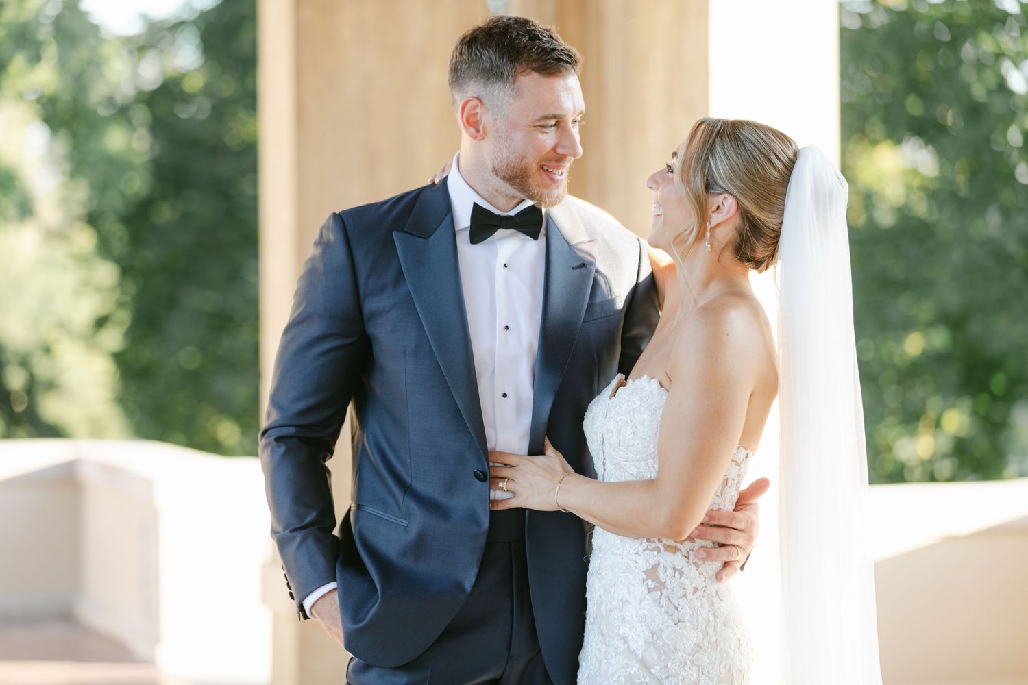 The Armour House Wedding - Bride and groom share a romantic moment outdoors near white columns.