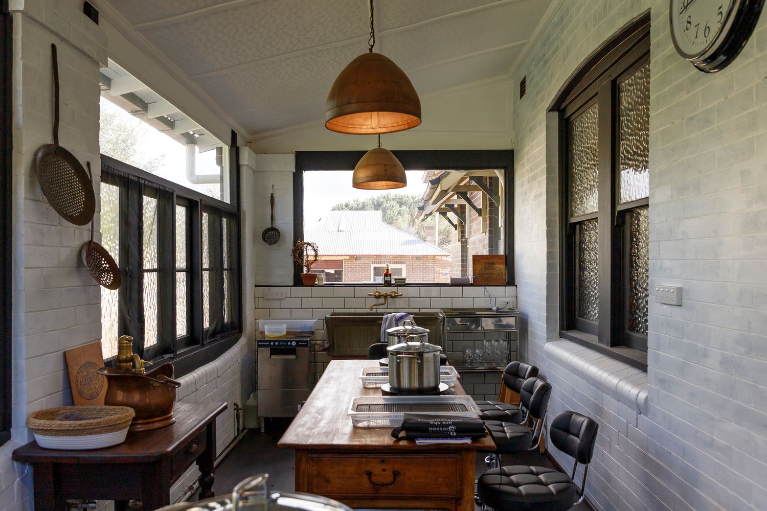 Picture of a black and white kitchen with a long centre table with cheese making equipment. Photo taken by Em Callaghan Photography.