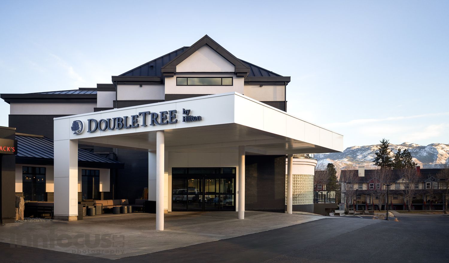 DoubleTree by Hilton hotel exterior with modern architecture, mountain views, and covered entrance at dusk.